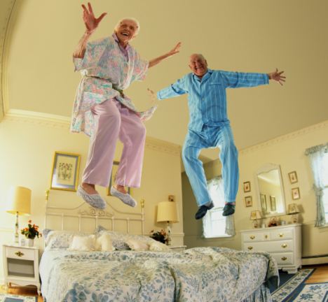 Elderly couple jumping on bed (Digital Composite)
